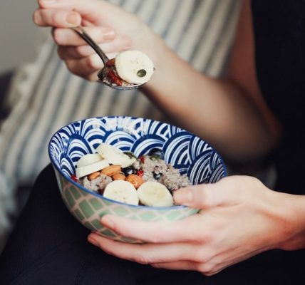 person holding spoon and bowl of food